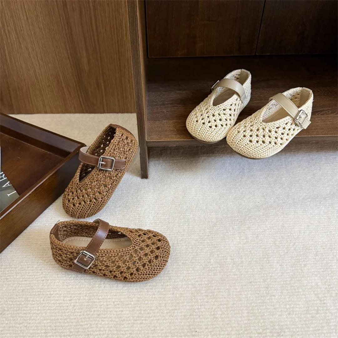 Beige and brown Mary Jane flats arranged on carpet by a cabinet