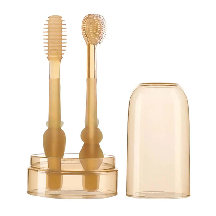 Two silicone baby toothbrushes in a storage cup with the matching cover beside them