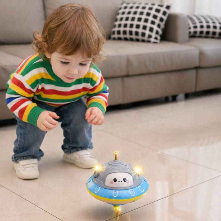 Child crouching beside a UFO balance toy spinning on a tiled floor.