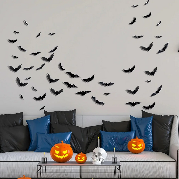 Unlit black bats arranged above a gray sofa with Halloween pumpkins on the coffee table
