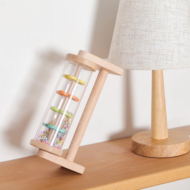 Wooden rain sound toy positioned upright beside a table lamp.