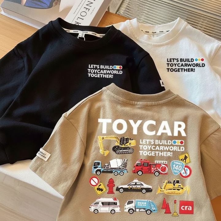 Black, white, and brown T-shirts showing small front lettering and a large vehicle design on the brown shirt