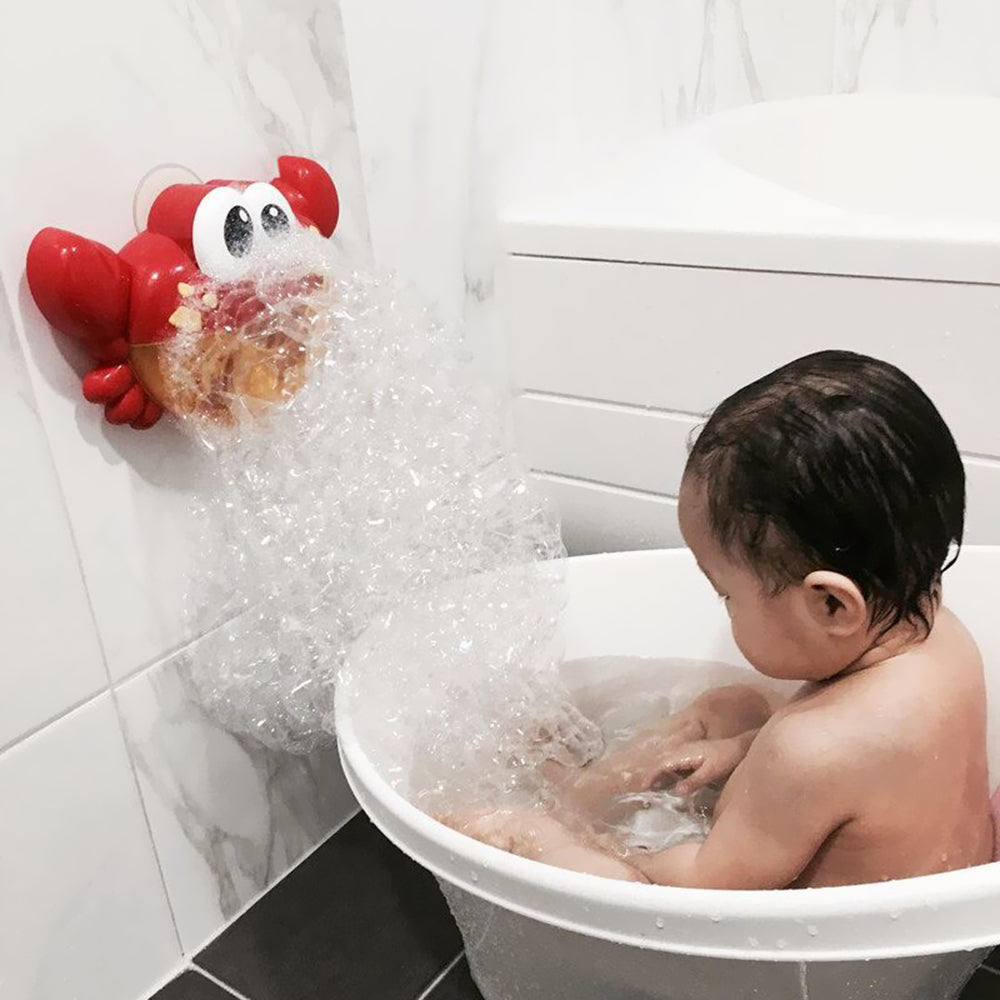 Red crab bubble bath toy mounted beside a bathtub with a child playing in the bubbles