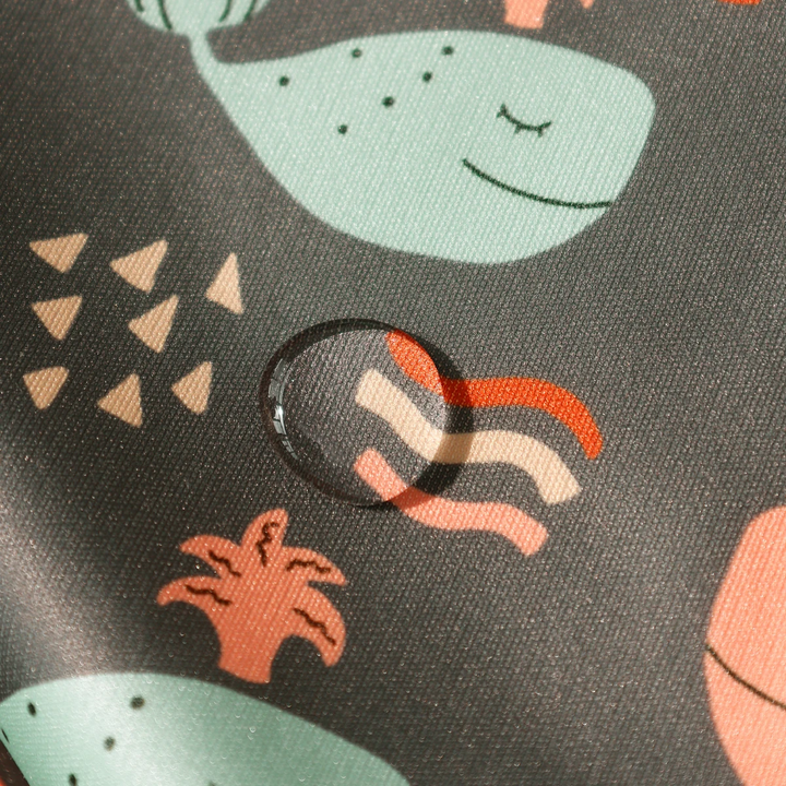 Water droplet resting on dark whale-print waterproof polyester fabric