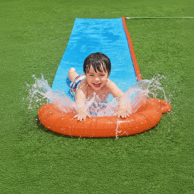 Child splashing into the orange landing bumper at the end of a blue water slide