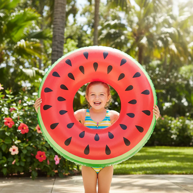 Child holding a watermelon-print swim ring on a poolside patio.