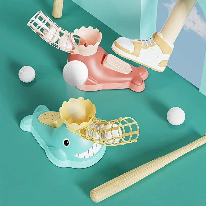 Two whale-shaped baseball pitchers with bats and balls, with a foot pressing the pink pitcher's pedal
