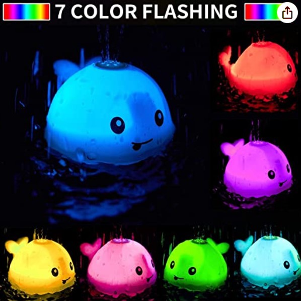 Whale bath toy glowing in seven colors against a dark background.