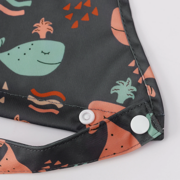 Close-up of snap fasteners and a fabric strap on a dark whale-print baby bib