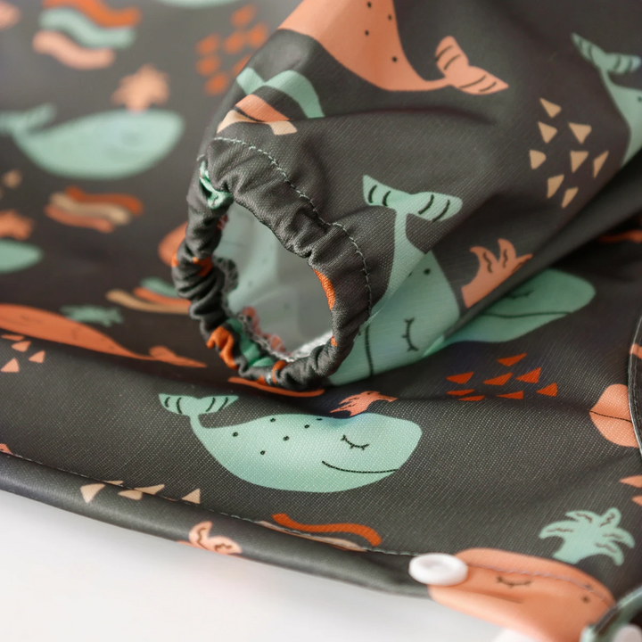 Gathered sleeve cuff on a dark whale-print long-sleeve baby bib