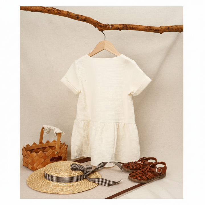 Back of the White A-line dress on a hanger, styled with a straw hat, basket, and sandals.