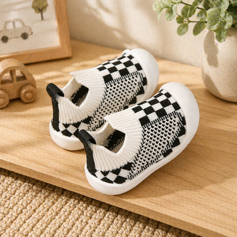White and black checkerboard baby sock shoes with knit cuffs and heel pull tabs.