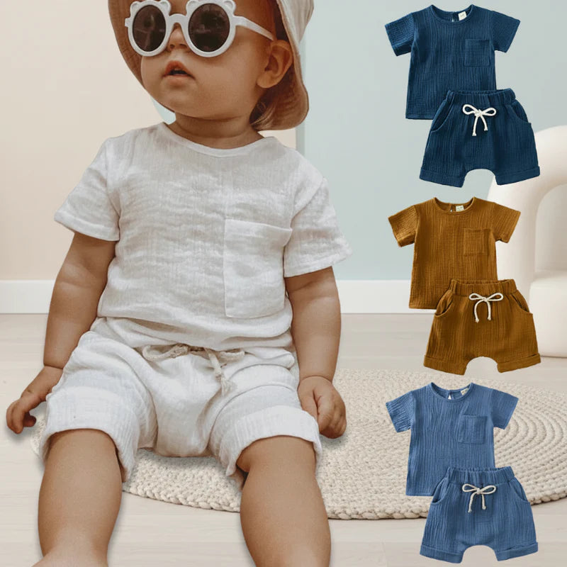 Baby wearing a white T-shirt and shorts set beside navy blue, brown, and blue outfit options.