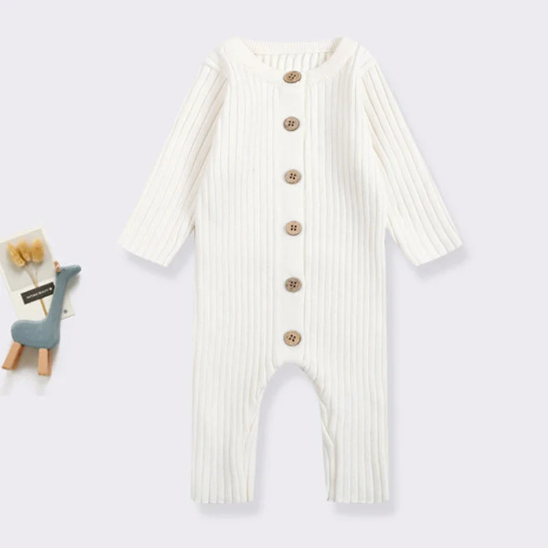 White baby romper laid flat, showing long sleeves, ribbed knit and front buttons