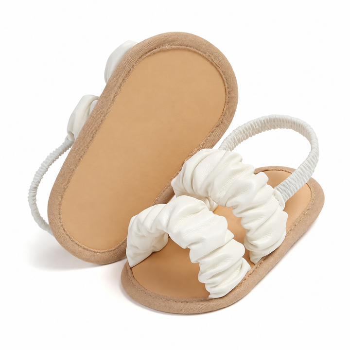 White baby sandals with one turned over to show the tan sole