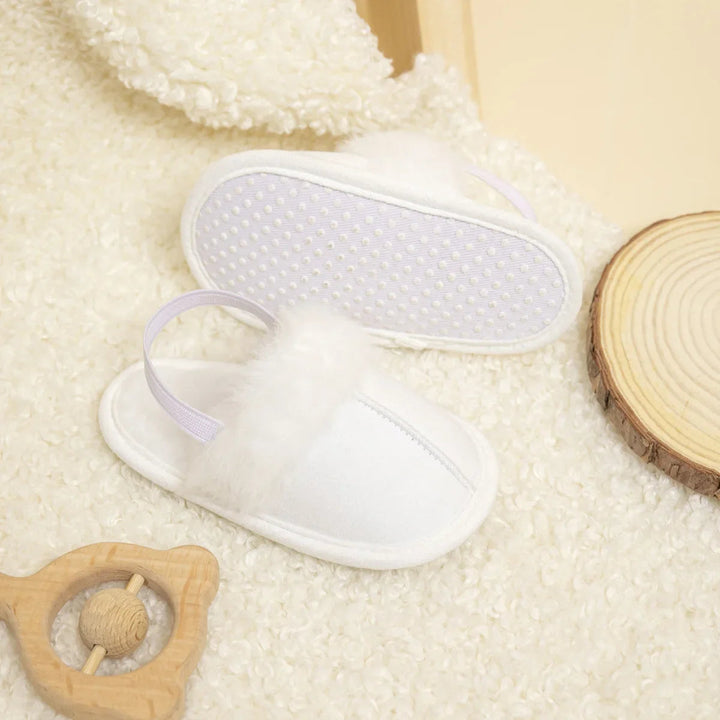 White baby slippers showing the plush upper and textured outsole