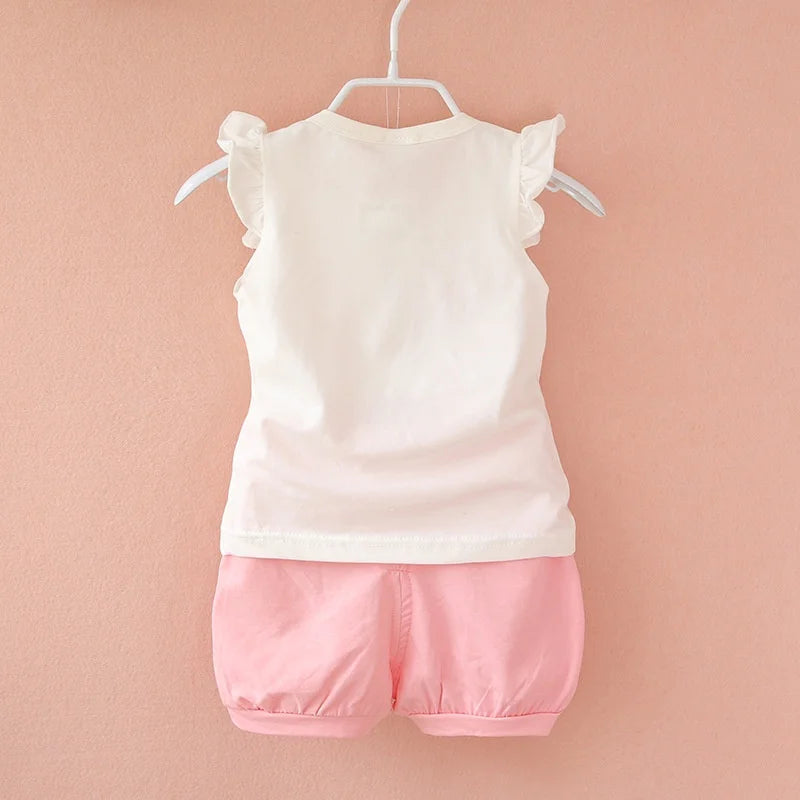 Back of a white ruffle-shoulder baby top paired with pale pink gathered-hem shorts