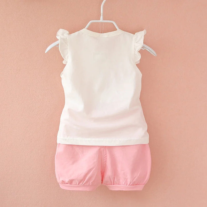 Back of a white ruffle-shoulder baby top paired with pale pink gathered-hem shorts
