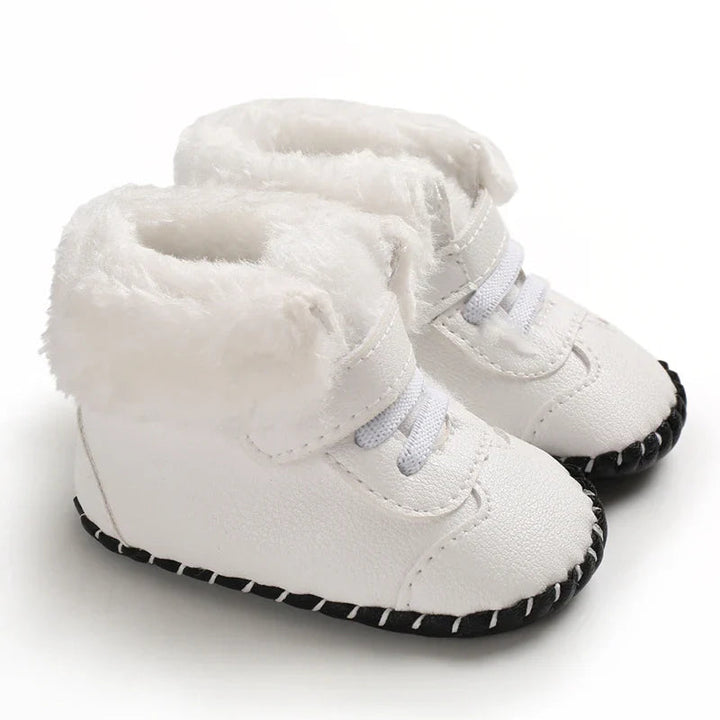 White baby winter boots with fluffy cuffs, front laces, and black soles