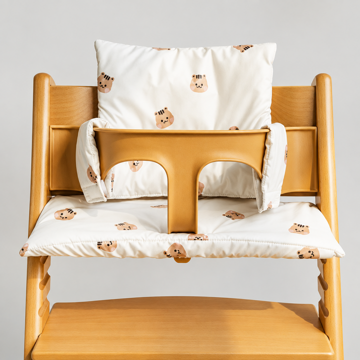 White high chair cushion with small bear faces, shown on a wooden chair