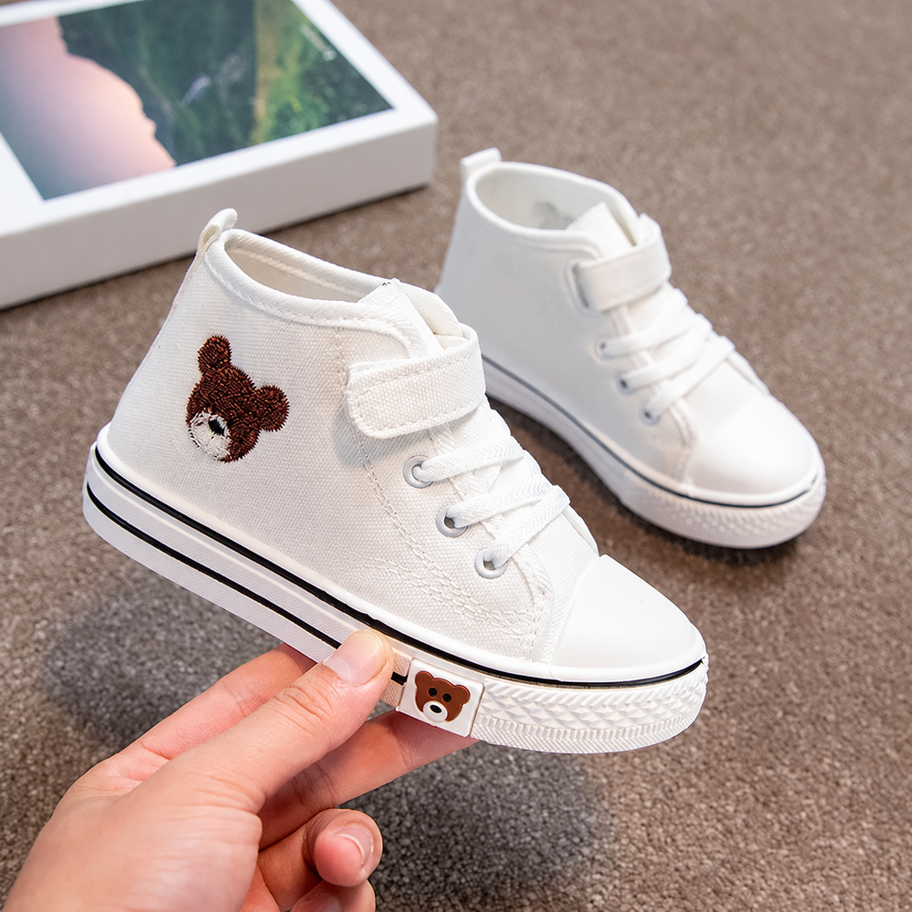 White high-top kids' sneaker held to show its bear detail and hook-and-loop ankle strap