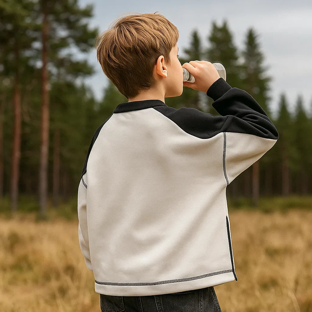 Back view of the white sweater with black sleeves, worn outdoors.