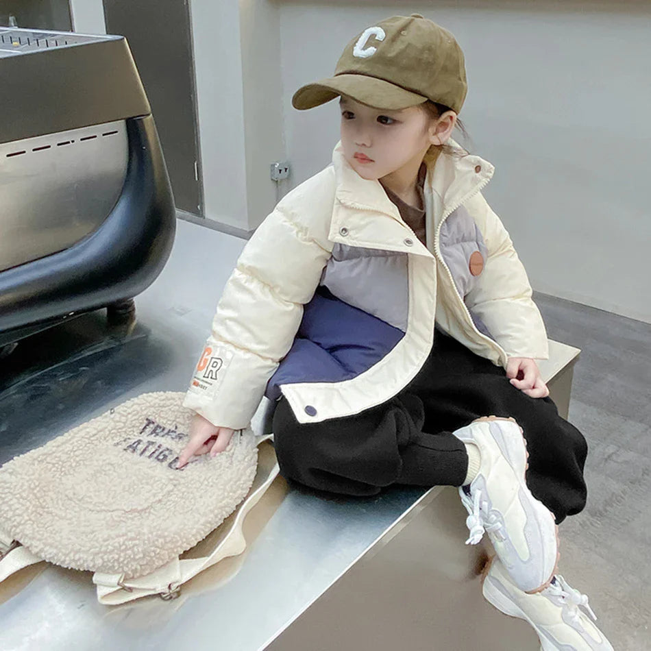 Child seated in a cream, gray, and navy winter coat worn open.