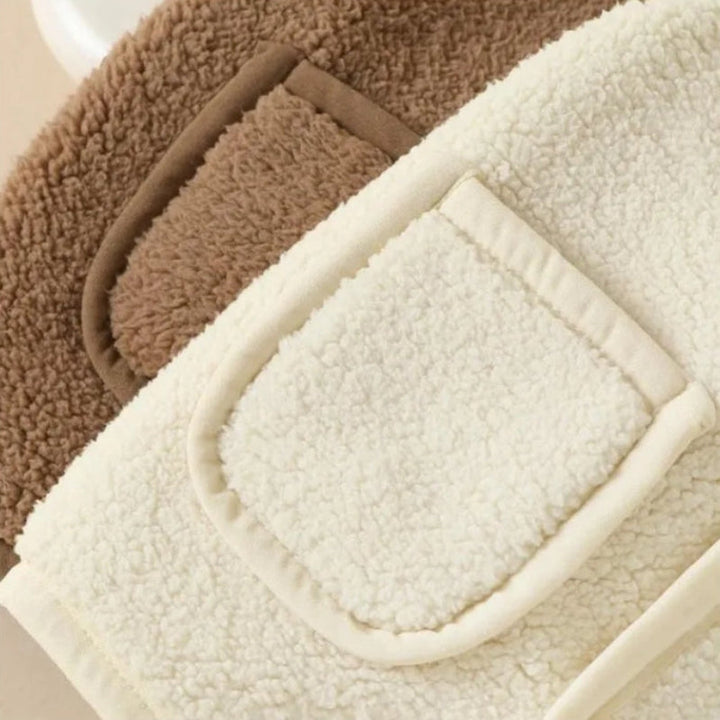 Front pocket details on white and brown fleece vests.