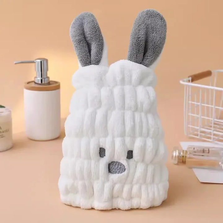 White bunny hair-drying cap with gray ears displayed beside a soap dispenser