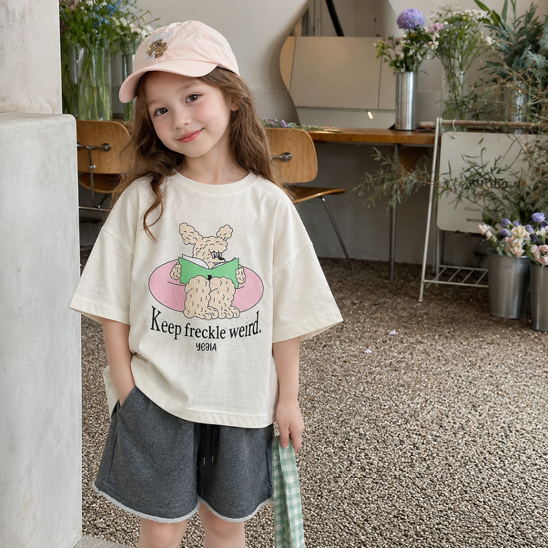 Girl in a white oversized cartoon T-shirt with a pink cap and gray shorts
