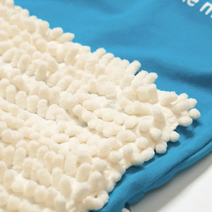Close-up of a textured white cleaning-fiber panel attached to blue jumpsuit fabric
