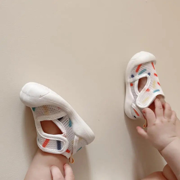 Baby wearing white mesh sandals with closed toes and side cutouts
