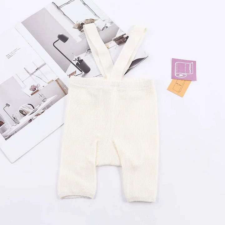 White ribbed suspender shorts laid flat with matching shoulder straps.
