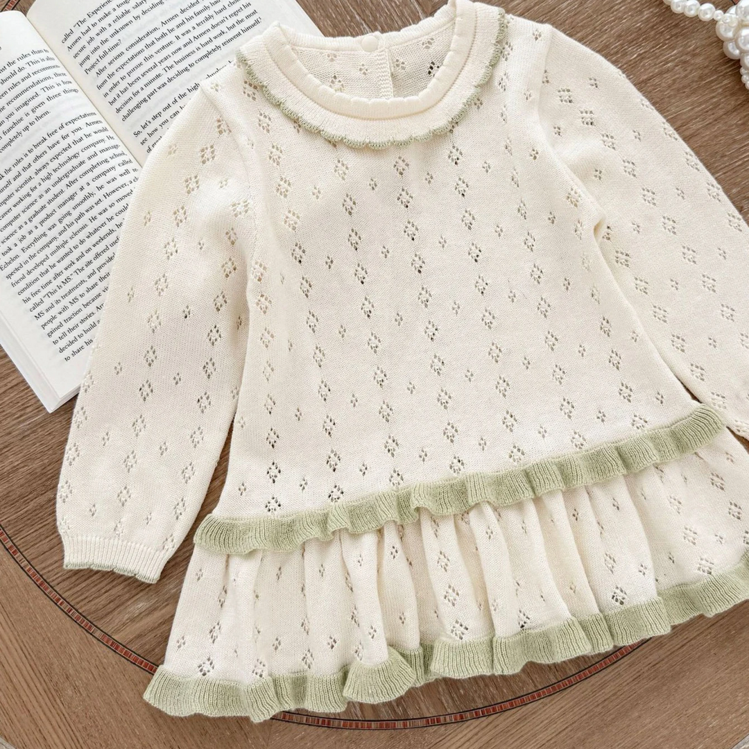 White long-sleeve knit baby dress with green skirt trim and a ruffled round neckline