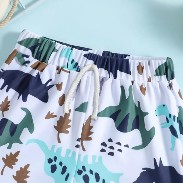Close-up of the elastic waistband and white drawstring on white dinosaur-print swim trunks