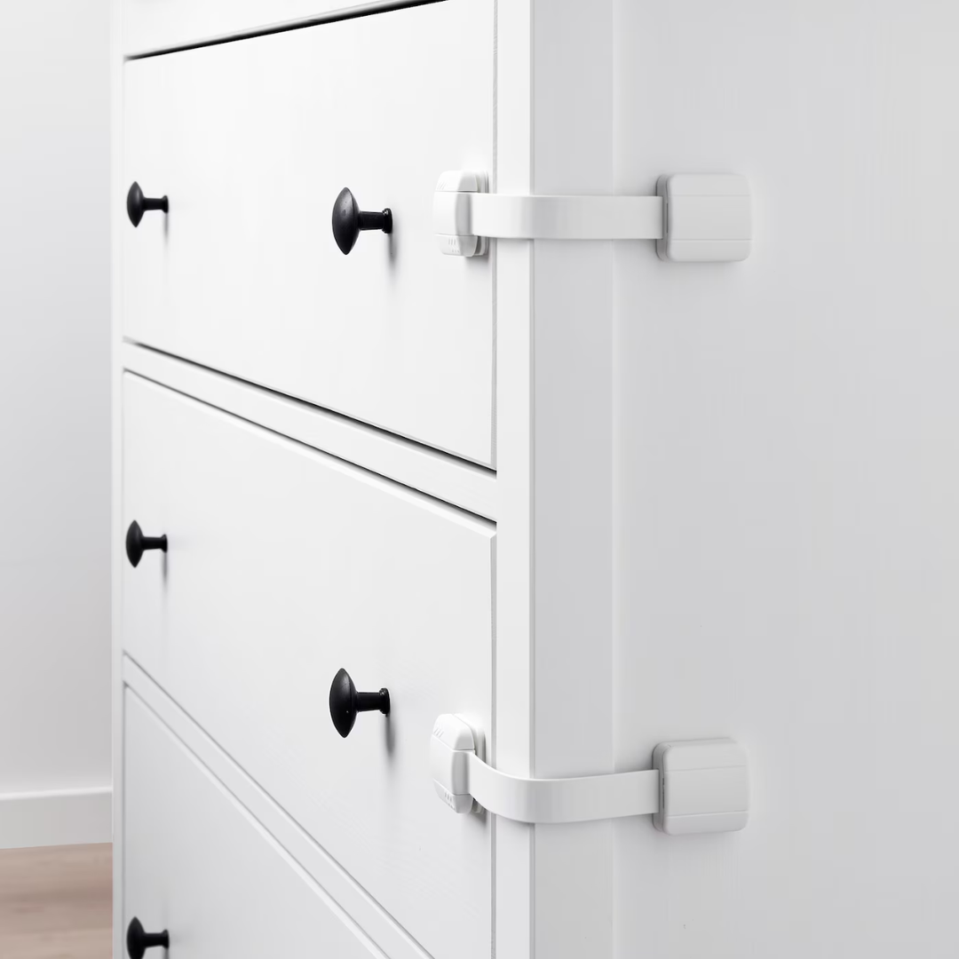 Two white strap locks attached to drawers on a white dresser
