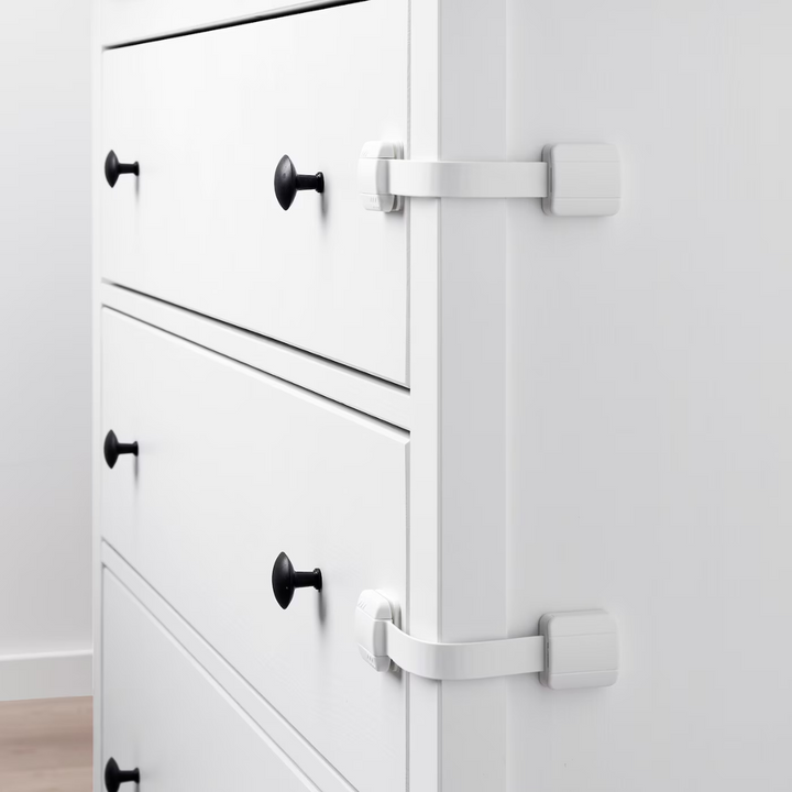 Two white strap locks attached to drawers on a white dresser