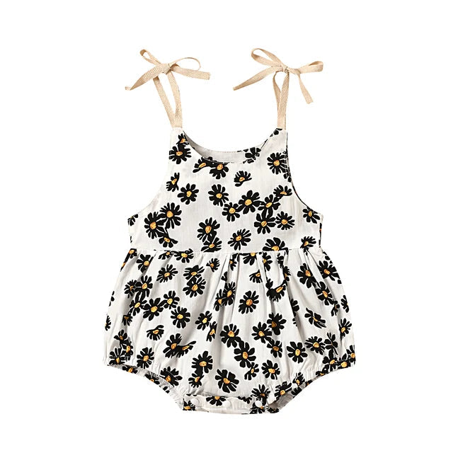 White baby romper with dark floral print, a gathered waist, and beige ties