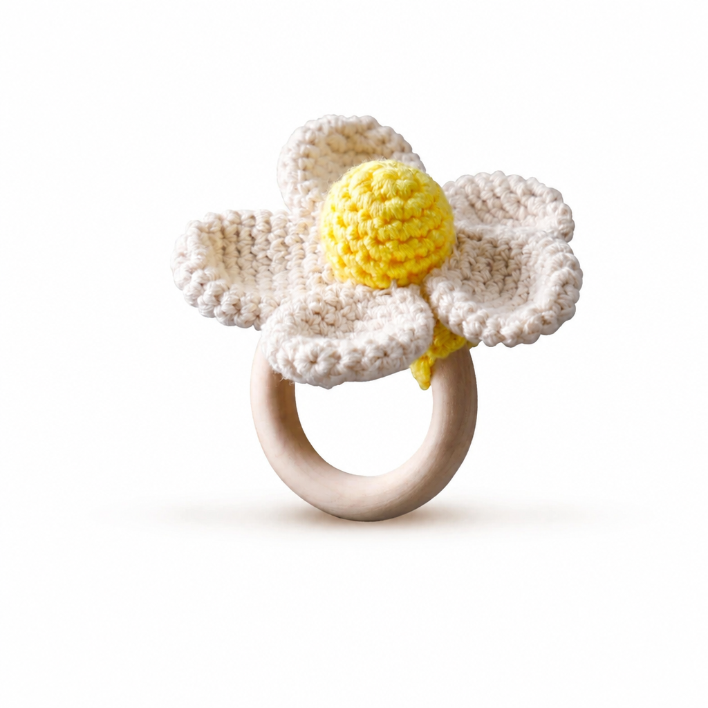 White crocheted flower rattle with a yellow center and wooden ring