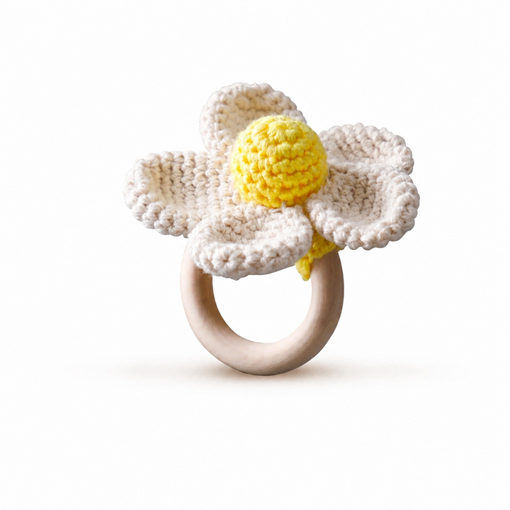 White crocheted flower rattle with a yellow center and wooden ring