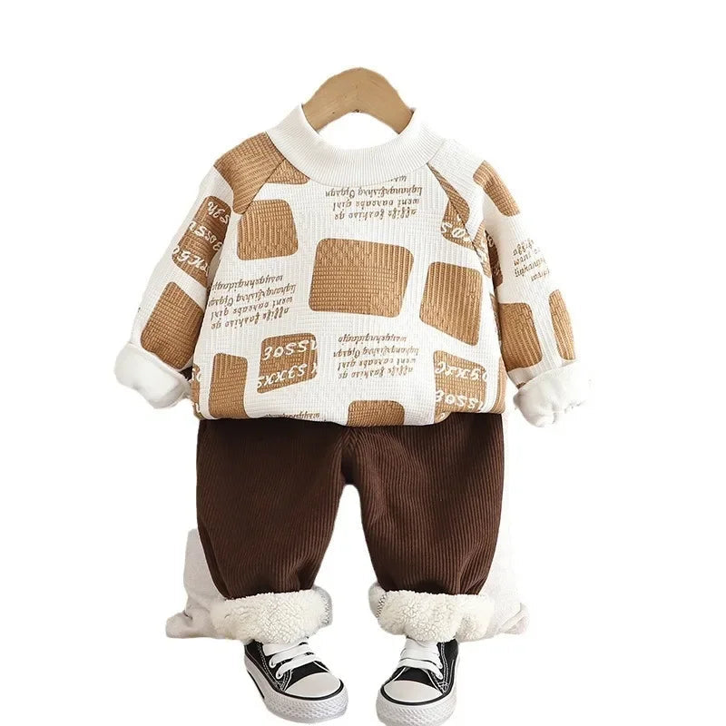 White and tan graphic sweater with brown pants, displayed on a white background