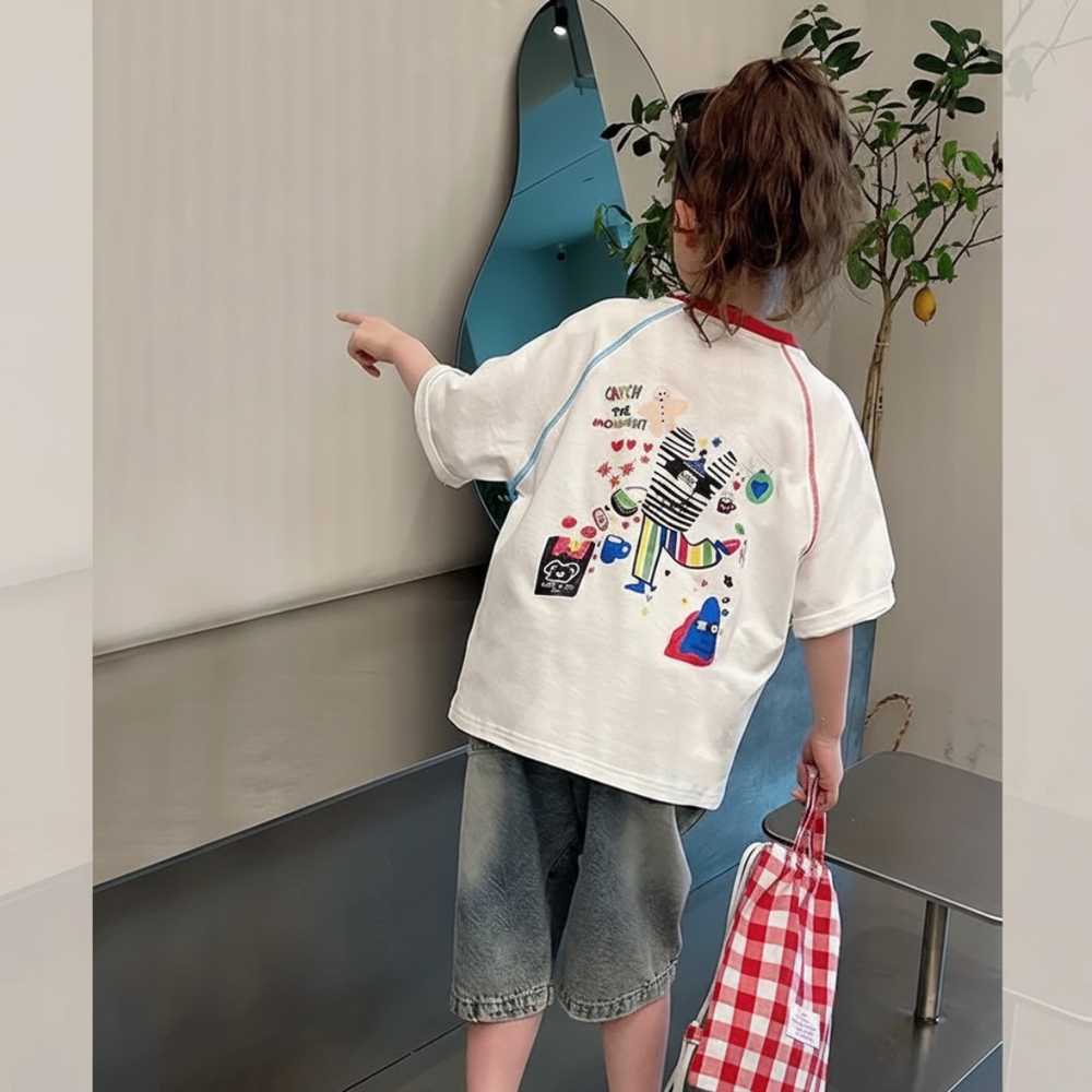 Back view of a child wearing the oversized graphic tee with long denim shorts