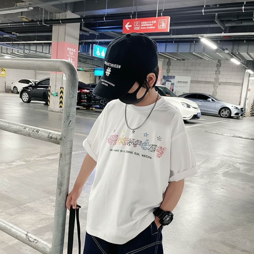 White graphic T-shirt styled with dark shorts and a black cap
