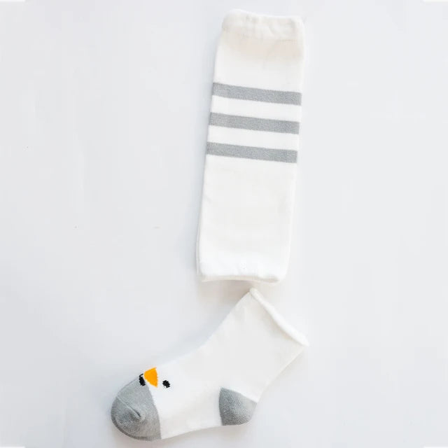 White leg warmer with gray stripes beside a white bird-face sock with a gray toe and heel.