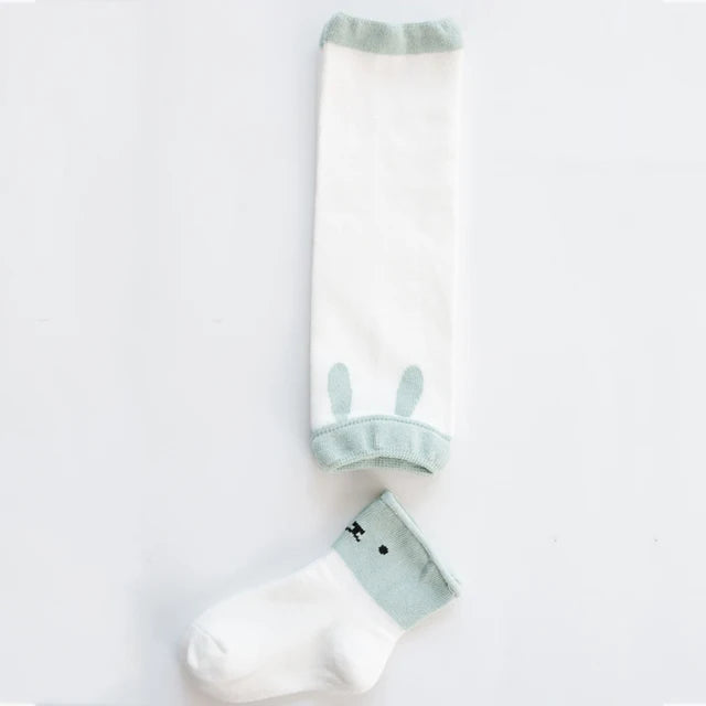 White leg warmer with pale green trim and bunny-ear details beside a coordinating animal-face sock.