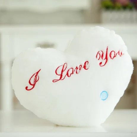 White heart-shaped plush pillow with red I Love You embroidery and a blue button