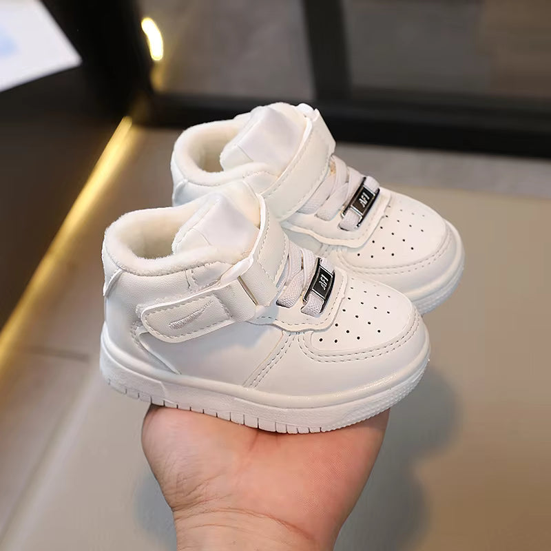 White high-top sneakers held in a hand, showing padded collars and wide straps