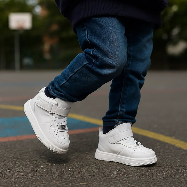 Child wearing white high-top sneakers with jeans on a painted playground