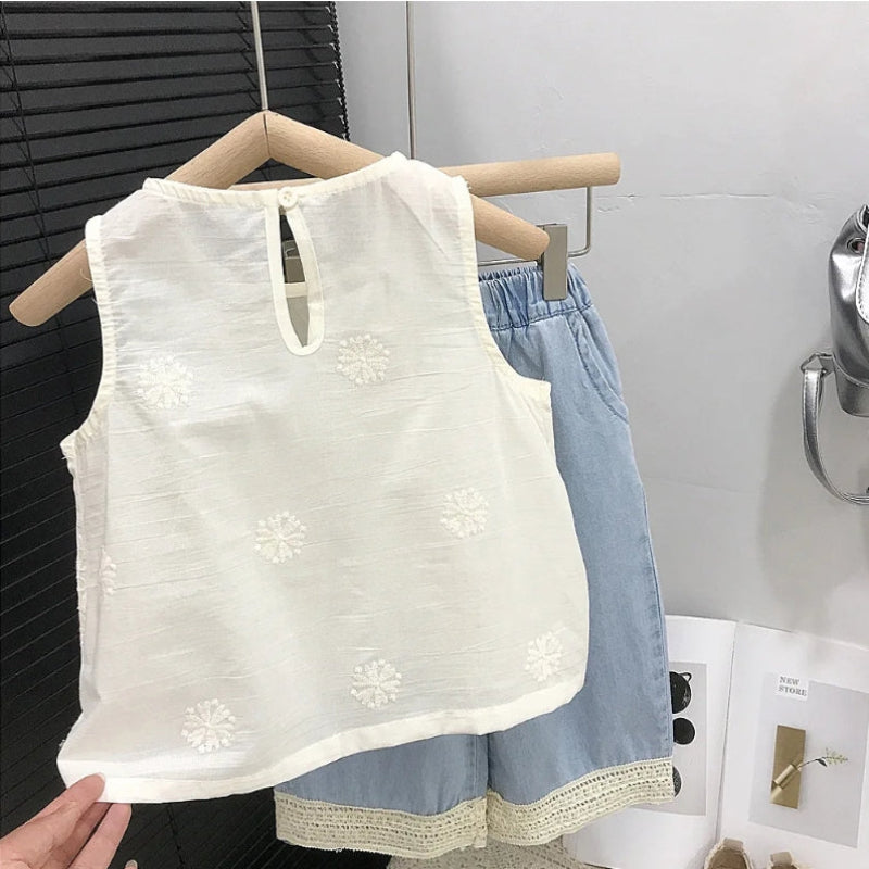 Back of a white sleeveless top with a keyhole neckline and blue lace-trimmed pants