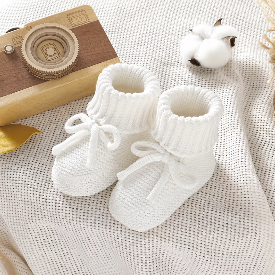 White knitted baby booties with folded cuffs and front ties